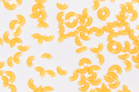 Scattered Uncooked Chifferi Rigati Pasta on White Background. Fat and Unhealthy Food. Classic Dry Macaroni Texture. Italian Culture and Cuisine. Raw Pastaの写真素材
