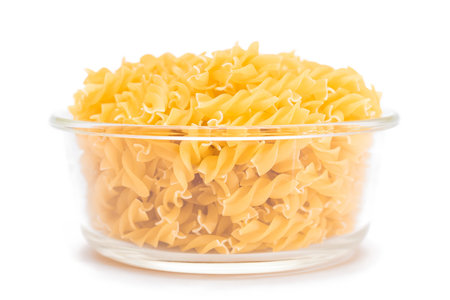 Uncooked Fusilli Pasta in Glass Jar Isolated on White Background. Fat and Unhealthy Food. Classic Dry Spiral Macaroni. Italian Culture and Cuisine. Raw Pastaの写真素材