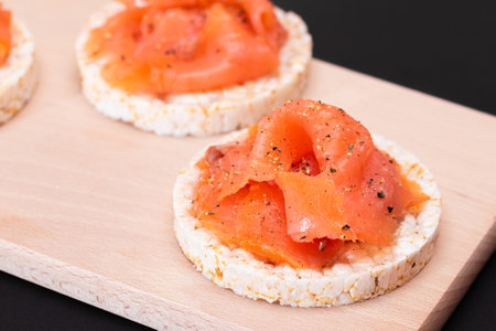 Tasty Rice Cake Sandwiches with Fresh Salmon Slices on Cutting Board - Close-Up. Easy Breakfast and Diet Food. Crispbread with Red Fish. Healthy Dietary Snackの写真素材