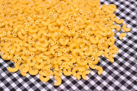 Scattered Uncooked Chifferi Rigati Pasta on Black Checkered Towel. Fat and Unhealthy Food. Classic Dry Macaroni. Italian Culture and Cuisine. Raw Pastaの写真素材