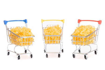Uncooked Fusilli Pasta in Three Small Shopping Carts Isolated on White Background. A Crisis: Buying Cheap Food. Classic Dry Spiral Macaroni. Italian Culture and Cuisine. Raw Pasta - Isolationの写真素材
