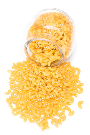 Uncooked Chifferi Rigati Pasta in Glass Jar Isolated on White Background. Fat and Unhealthy Food. Scattered Classic Dry Macaroni. Italian Culture and Cuisine. Raw Pastaの写真素材