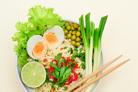 Beautiful Noodle Dish with Green Onions, Eggs, Green Pea, Red Hot Pepper, Greens and Lime on White Background. Instant Noodles with Vegetables - Top Viewの写真素材