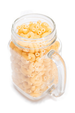 Uncooked Chifferi Rigati Pasta in Glass Jar Isolated on White Background. Fat and Unhealthy Food. Classic Dry Macaroni. Italian Culture and Cuisine. Raw Pasta - Isolationの写真素材