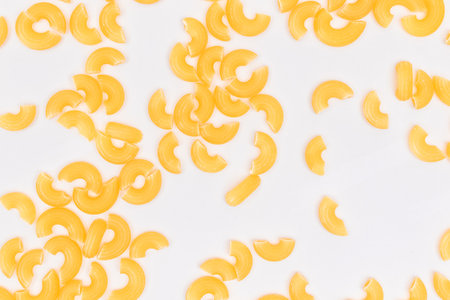 Scattered Uncooked Chifferi Rigati Pasta on White Background. Fat and Unhealthy Food. Classic Dry Macaroni Texture. Italian Culture and Cuisine. Raw Pastaの写真素材