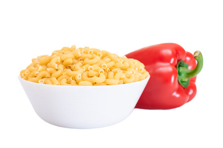 Uncooked Chifferi Rigati Pasta in White Cup with Red Bell Pepper Isolated on White Background. Fat and Unhealthy Food. Classic Dry Macaroni. Italian Culture and Cuisine. Raw Pasta - Isolationの写真素材