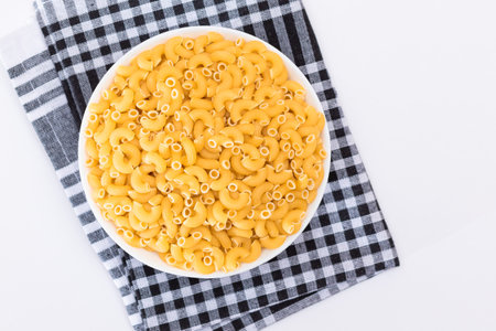 Uncooked Chifferi Rigati Pasta in White Cup on Black Checkered Towel. Fat and Unhealthy Food. Classic Dry Macaroni. Italian Culture and Cuisine. Raw Pastaの写真素材