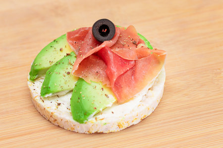 Rice Cake Sandwich with Fresh Avocado, Jamon and Olives on Bamboo Cutting Board. Easy Breakfast. Diet Food. Quick and Healthy Sandwiches. Crispbread with Tasty Filling. Healthy Dietary Snackの写真素材