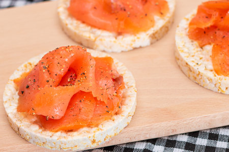 Tasty Rice Cake Sandwiches with Fresh Salmon Slices on Wooden Cutting Board. Easy Breakfast and Diet Food. Crispbread with Red Fish. Healthy Dietary Snackの写真素材