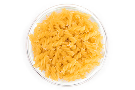 Uncooked Fusilli Pasta in Glass Jar Isolated on White Background. Fat and Unhealthy Food. Classic Dry Spiral Macaroni. Italian Culture and Cuisine. Raw Pastaの写真素材