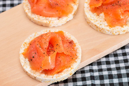 Tasty Rice Cake Sandwiches with Fresh Salmon Slices on Cutting Board - Top View. Easy Breakfast and Diet Food. Crispbread with Red Fish. Healthy Dietary Snackの写真素材