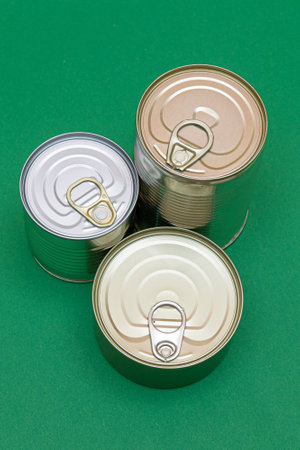 A Group of Stacked Tin Cans with Blank Edges on Green Background. Canned Food. Different Aluminum Cans for Safe and Long Term Storage of Food. Steel Sealed Food Storage Containersの写真素材