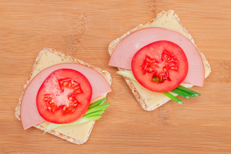 Rice Cake Sandwich with Tomato, Sausage, Green Onions and Cheese on Wooden Cutting Board. Easy Breakfast. Diet Food. Quick and Healthy Sandwiches. Crispbread with Tasty Filling. Healthy Dietary Snackの写真素材