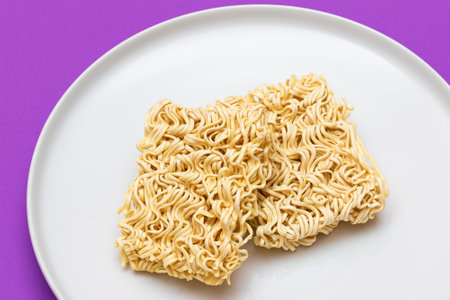 Uncooked Instant Noodles on White Plate. Raw Pasta. Dry Asian Fast Food. Quick Lunchの写真素材
