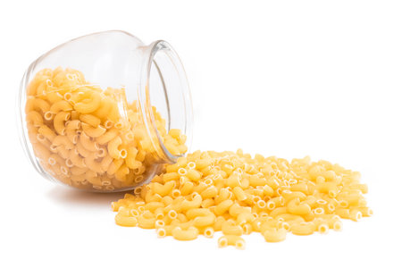 Uncooked Chifferi Rigati Pasta in Glass Jar Isolated on White Background. Fat and Unhealthy Food. Scattered Classic Dry Macaroni. Italian Culture and Cuisine. Raw Pastaの写真素材