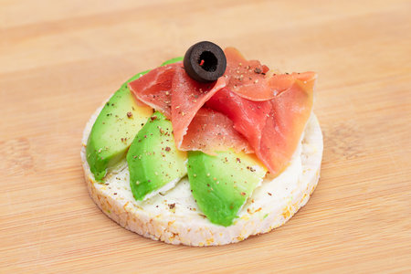 Rice Cake Sandwich with Fresh Avocado, Jamon and Olives on Bamboo Cutting Board. Easy Breakfast. Diet Food. Quick and Healthy Sandwiches. Crispbread with Tasty Filling. Healthy Dietary Snackの写真素材