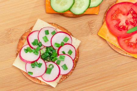Different Cracker Sandwiches with Tomato, Cucumber, Radish and Cheese on Cutting Board. Easy...