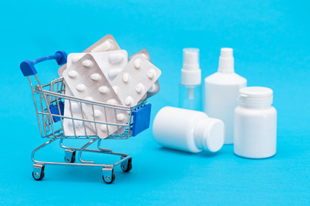 Buying Medicines. Expensive Medicine and Inflation Concept: Pills and Capsules in Shopping Cart on Blue Background. Global Pharmaceutical Industry and Big Pharma. Ordering Pharmaceutical Productsの写真素材