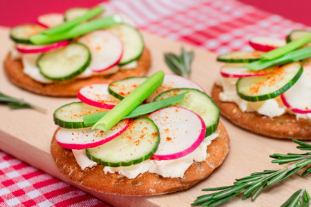 Light Breakfast or Diet Eating - Crispy Cracker Sandwich with Cream Cheese, Fresh Cucumber, Green Onions and Radish on Wooden Cooking Board on Magenta Backgroundの写真素材