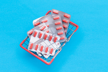 Buying Medicines. Drug Addiction Concept: Pills and Capsules in Shopping Basket on Blue Background. Global Pharmaceutical Industry and Big Pharma. Ordering Pharmaceutical Productsの写真素材