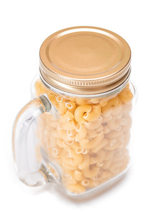 Uncooked Chifferi Rigati Pasta in Glass Jar Isolated on White Background. Fat and Unhealthy Food. Classic Dry Macaroni. Italian Culture and Cuisine. Raw Pasta - Isolationの写真素材