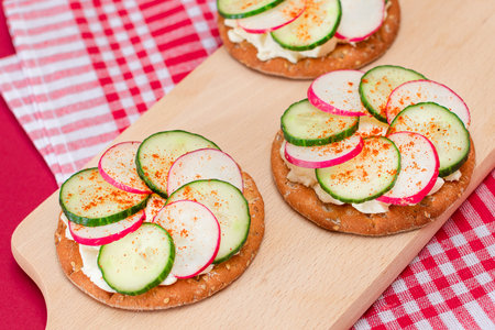 Light Breakfast or Diet Eating - Crispy Cracker Sandwich with Cream Cheese, Fresh Cucumber and Radish on Wooden Cooking Board on Magenta Backgroundの写真素材