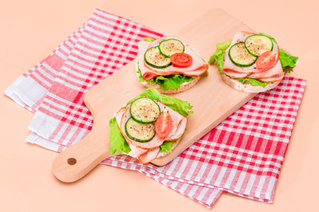 Light Breakfast. Quick and Healthy Sandwiches. Rice Cake with Ham, Tomato, Fresh Cucumber and Green Salad on Wooden Cutting Boardの写真素材