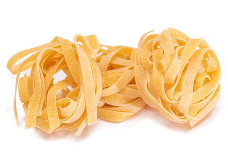 Three Classic Italian Raw Egg Fettuccine - Isolated on White Background. Dry Twisted Uncooked Pasta. Italian Culture and Cuisine. Raw Golden Macaroni Pattern - Isolationの写真素材