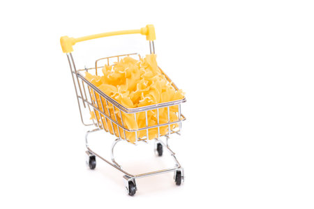 Uncooked Fusilli Pasta in Small Shopping Cart Isolated on White Background. A Crisis: Buying Cheap Food. Classic Dry Spiral Macaroni. Italian Culture and Cuisine. Raw Pasta - Isolationの写真素材