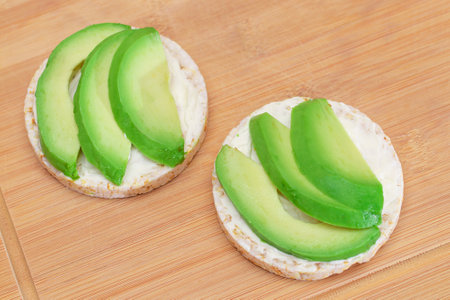 Rice Cake Sandwiches with Fresh Avocado and Cream Cheese on Bamboo Cutting Board. Easy Breakfast. Diet Food. Quick and Healthy Sandwiches. Crispbread with Tasty Filling. Healthy Dietary Snackの写真素材
