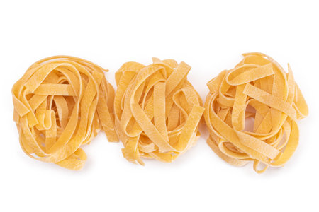 Three Classic Italian Raw Egg Fettuccine - Isolated on White Background. Dry Twisted Uncooked Pasta. Italian Culture and Cuisine. Raw Golden Macaroni Pattern - Isolationの写真素材