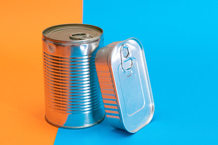 A Group of Stacked Tin Cans with Blank Edges on Split Blue and Orange Background. Canned Food....