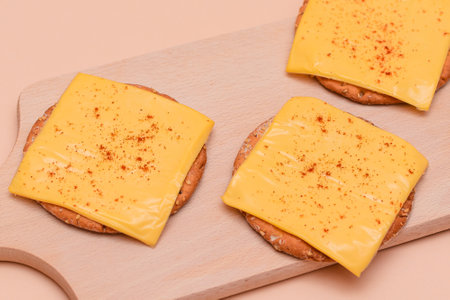 Crispy Cracker Sandwiches with Cheese and Paprika on Wooden Cutting Board and Beige Backgroundの写真素材