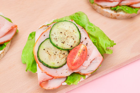 Light Breakfast. Quick and Healthy Sandwiches. Rice Cakes with Ham, Tomato, Fresh Cucumber and Green Salad on Wooden Cutting Boardの写真素材