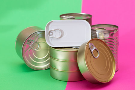 A Group of Stacked Tin Cans on Split Green and Cyan Background. Canned Food. Aluminum Cans for Safe...