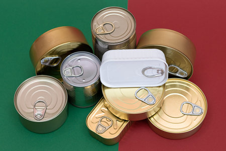 A Group of Stacked Tin Cans on Split Red and Green Background. Canned Food. Aluminum Cans for Safe...