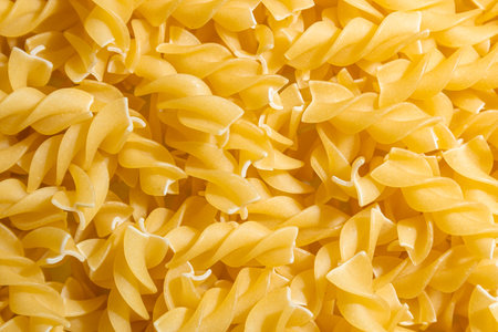 Uncooked Fusilli Pasta: A Culinary Canvas of Spiral Macaroni, Creating a Lively and Textured Background for Gourmet Cooking. Dry Pasta. Raw Macaroni - Top View, Flat Layの写真素材