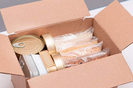 Food Reserves or Donation Box: Carton Box with Canned Food, Cereals and Grocery. Emergency Food Storage in Case of Crisis. Free Social Help, Blessings and Care. Strategic Food Suppliesの写真素材