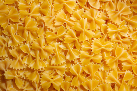 Uncooked Farfalle Pasta: A Culinary Canvas of Bow-Tie Macaroni, Creating a Lively and Textured Background for Gourmet Cooking. Dry Pasta. Raw Macaroni - Top View, Flat Layの写真素材