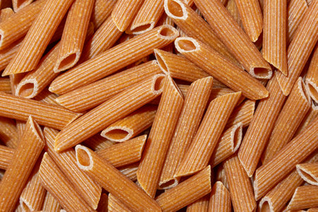 Uncooked Whole Grain Penne Rigate Pasta: A Culinary Canvas of Whole Wheat Macaroni, Creating a Lively and Textured Background for Gourmet Cooking. Whole Grain Dry Pasta. Whole Wheat Raw Macaroniの写真素材