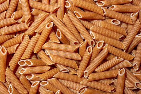 Uncooked Whole Grain Penne Rigate Pasta: A Culinary Canvas of Whole Wheat Macaroni, Creating a Lively and Textured Background for Gourmet Cooking. Whole Grain Dry Pasta. Whole Wheat Raw Macaroniの写真素材