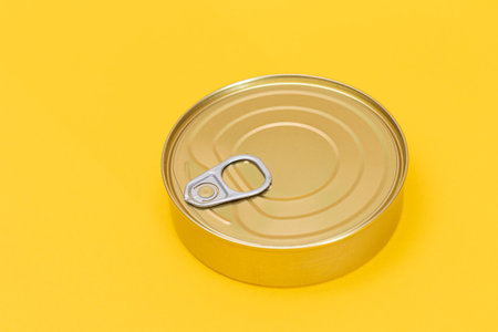 Tin Can on Yellow Background. Canned Food. Aluminum Can for Safe and Long Term Storage of Food. Steel Sealed Food Storage Containerの写真素材