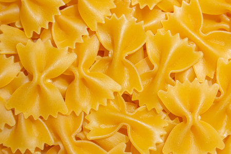 Uncooked Farfalle Pasta: A Culinary Canvas of Bow-Tie Macaroni, Creating a Lively and Textured Background for Gourmet Cooking. Dry Pasta. Raw Macaroni - Top View, Flat Layの写真素材
