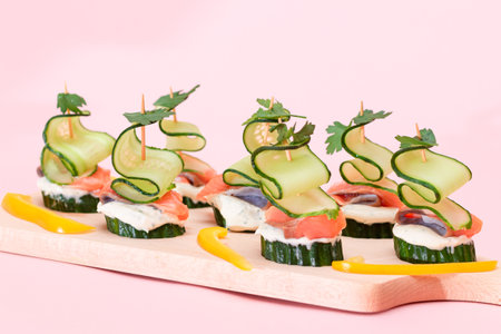 Canapes without Bread with Fresh Salmon, Cucumber and Cream Cheese on Wooden Cutting Board. Easy Breakfast. Diet Food. Quick and Healthy Sandwiches. Healthy Snacks with Tasty Fillingsの写真素材