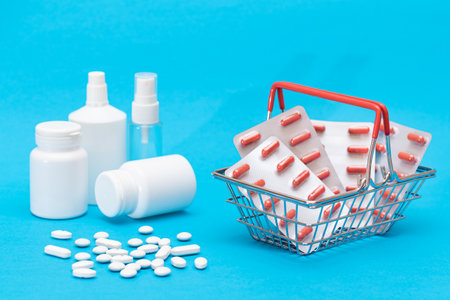 Buying Medicines. Expensive Medicine and Inflation Concept: Pills and Capsules in Shopping Basket on Blue Background. Global Pharmaceutical Industry and Big Pharma. Ordering Pharmaceutical Productsの写真素材