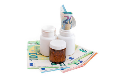 Different Bottles with Pills, Capsules and Medicines on the Euro Banknotes - Isolated on White. Global Pharmaceutical Industry and Big Pharma. Euro Money Bills - Isolationの写真素材