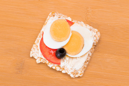 Rice Cake Sandwich with Tomato, Eggs and Olives on Bamboo Cutting Board. Easy Breakfast. Diet Food. Quick and Healthy Sandwiches. Crispbread with Tasty Filling. Healthy Dietary Snackの写真素材