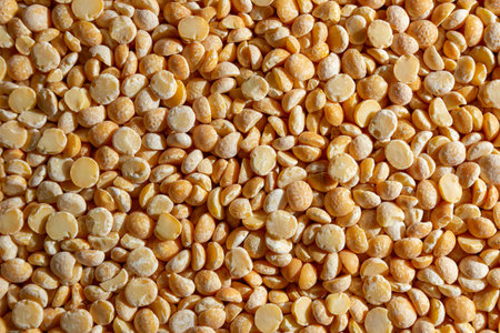 Uncooked Polished Split Peas Background. A Culinary Canvas of Dry Yellow Peas, Creating a Lively and Textured Background for Gourmet Cooking. Scattered Raw Polished Peas. Healthy Eating Ingredientsの写真素材