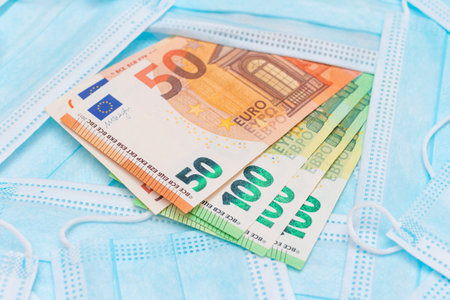 Euro Banknotes with Blue Disposable Medical Face Masks. Trade in Medical Masks. Business During a Pandemic or Epidemicの写真素材