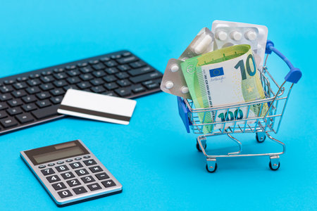 Ordering Medicines. Expensive Medicine and Inflation Concept: Pills and Capsules in a Shopping Cart on Blue Background. Global Pharmaceutical Industry and Trade in Medicinesの写真素材